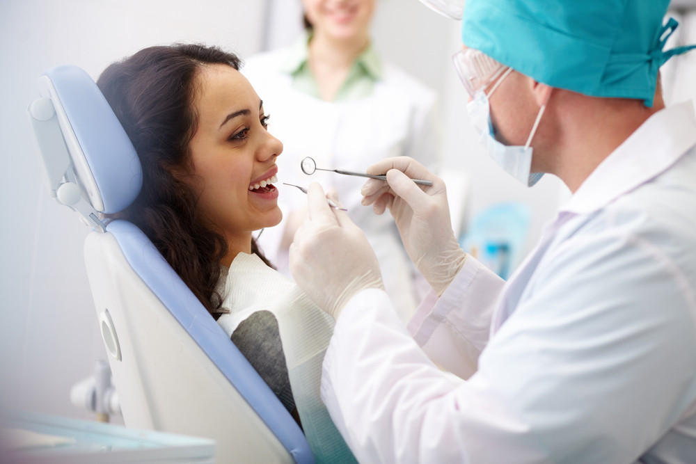 Dentist examining woman’s teeth during an oral health checkup.